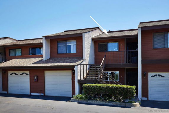 Front view of a multi-story townhouse with garages and exterior stairs.