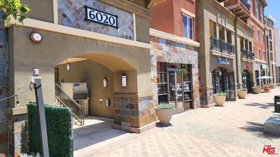Street view of a commercial building with a patterned facade and an arched entrance.