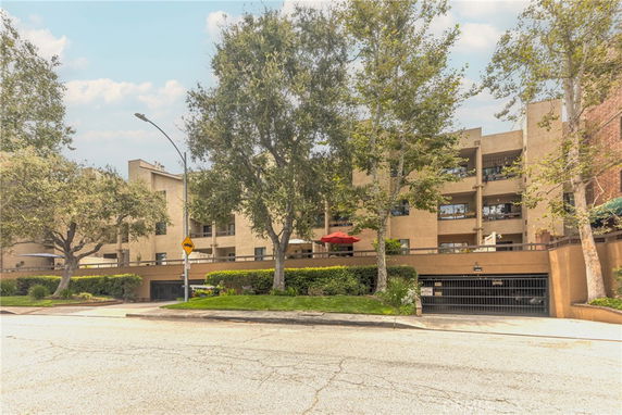Front view of a multi-story building with balconies and an entrance to an underground parking area.