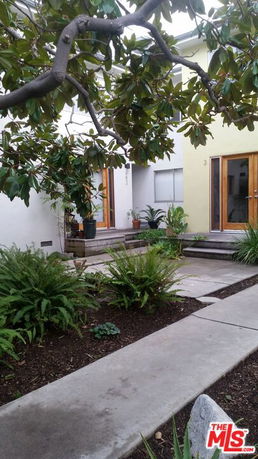 Front view of a house with a small garden and wooden doors.