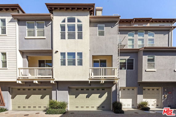 Front view of a row of multi-story townhouses with balconies and garages.