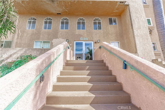 Front view of a multi-story building with a staircase leading to the entrance.