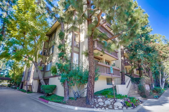 Front view of a multi-story building with balconies and trees around.
