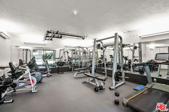Indoor gym area with exercise equipment and mirrors on the walls.