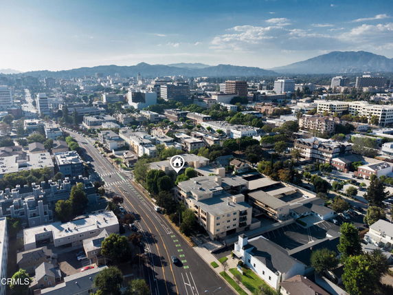 Aerial view of a city with numerous buildings and roads, and distant mountains in the background.