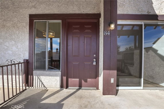 Front entrance of a house with a brown door and adjacent windows.