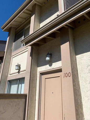 Detailed view of a two-story building's facade with windows and a door marked 100.