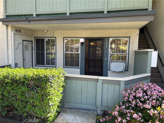 Front view of a lower-level apartment with a small porch and numbered entry door.