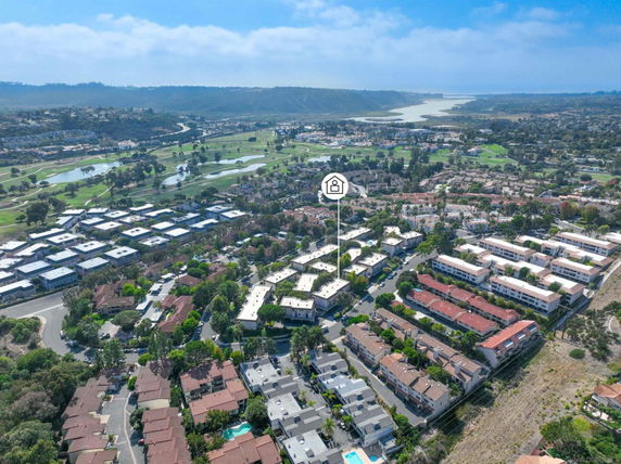 Aerial view of a residential area with numerous buildings and a golf course in the background.