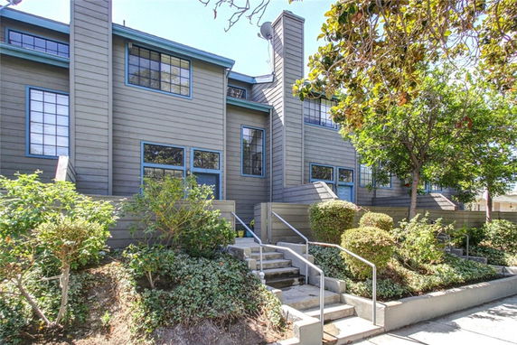 Front view of a multi-story building with large windows and a staircase leading to the entrance.