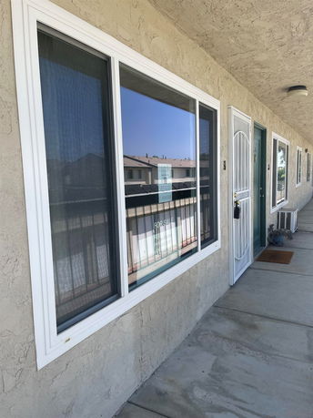 Exterior view of a building corridor with windows and doors.