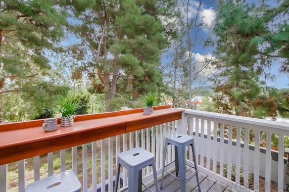 Balcony with stools and plants overlooking trees.