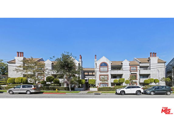 Front view of a multi-story residential building with multiple balconies and chimney structures.