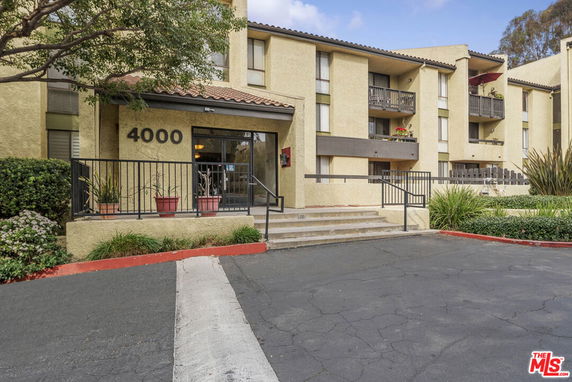 Front view of a multi-story apartment building with balconies and a central entrance.
