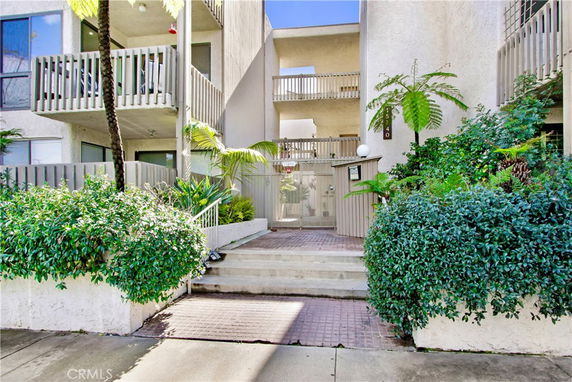 Front view of a multi-story residential building with balconies and greenery.