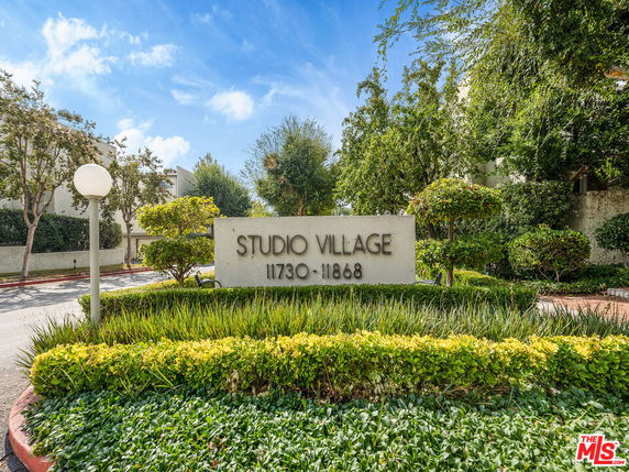 Entrance sign of a residential area with greenery and trees surrounding it.