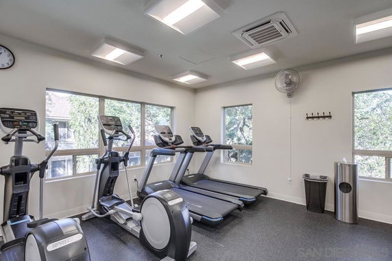 Indoor gym area with exercise equipment and large windows.