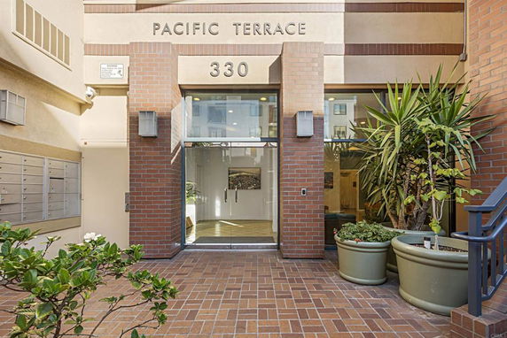 Entrance of a building labeled 'Pacific Terrace' with glass doors and brick exterior.