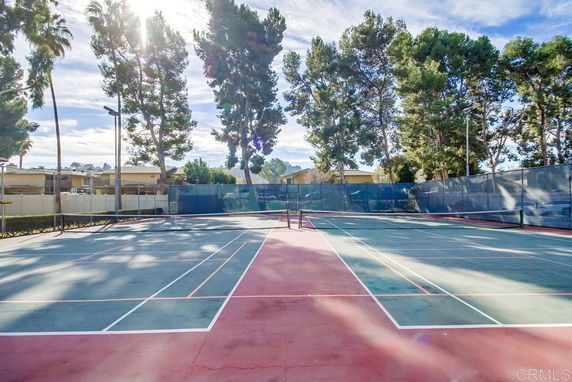 Tennis court surrounded by trees and buildings.