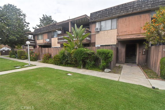 Front view of a multi-story residential building with wooden exterior and balconies.