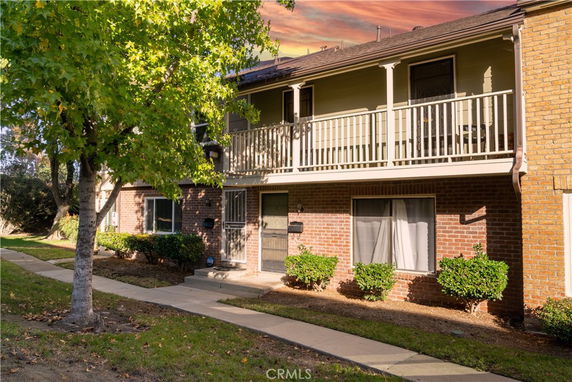 Front view of a two-story residential building with a balcony and brick exterior.