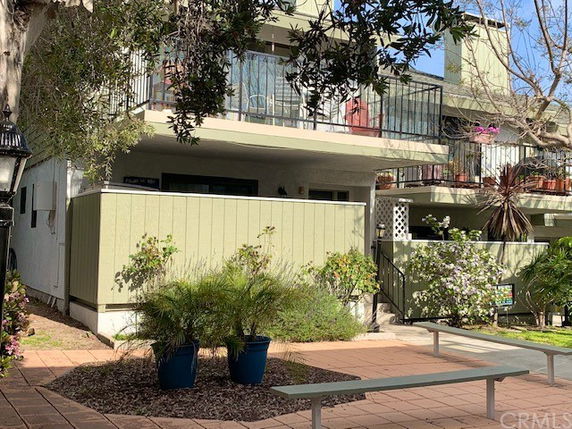 Front view of a two-story residential building with balconies and potted plants.