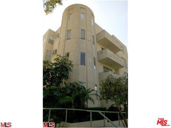 Front view of a multi-story building with balconies and a rounded corner section.