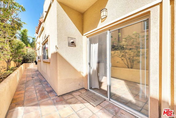 Exterior view of a building with sliding glass doors and tiled pathway