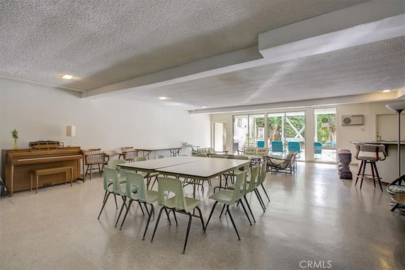 Large indoor recreational space with tables, chairs, and a piano.