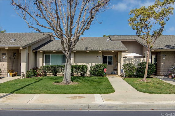 Front view of a single-story residential building with a small lawn and trees.