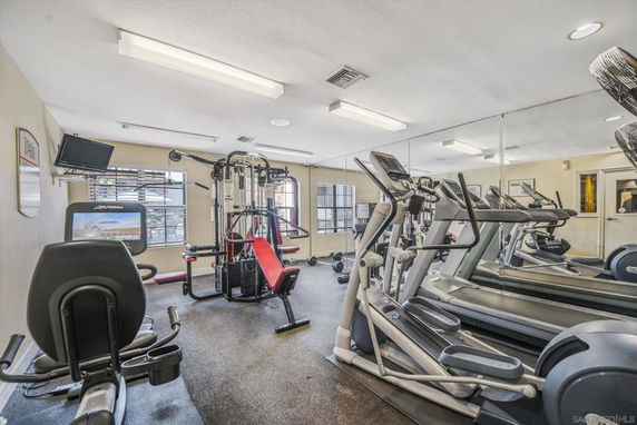 Indoor fitness room with exercise machines and mirrors.