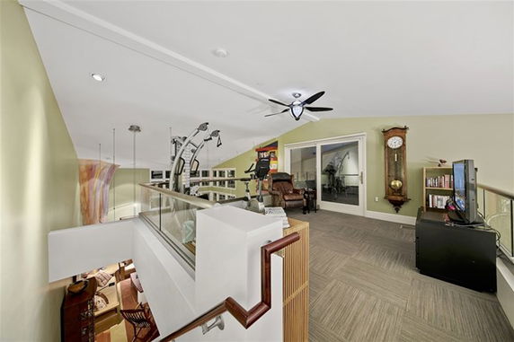 Indoor recreational area with exercise equipment, seating, a clock, and a small bookshelf.