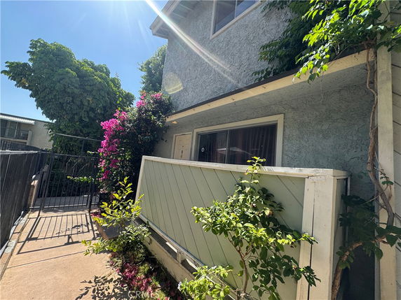 Front view of a two-story house with a small gated entrance and plants.