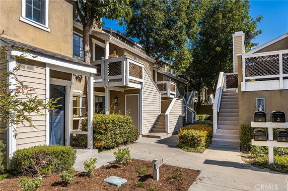 Front view of a multi-story residential building with external staircases and mailboxes.