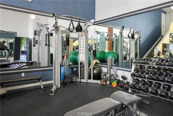 Gym area with mirrors, workout equipment, and dumbbells.