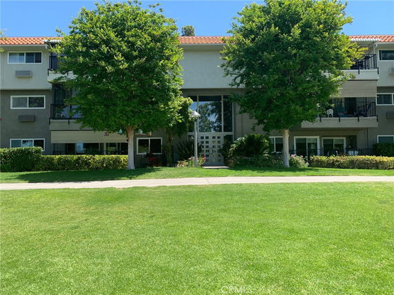 Front view of a multi-story building with balconies and large entrance windows.