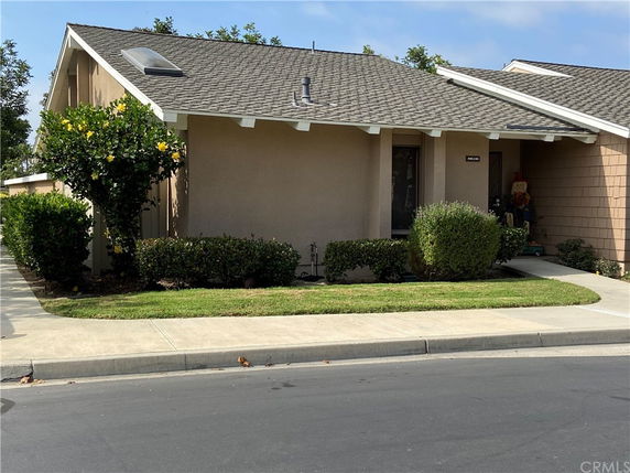 Front view of a single-story house with a sloped roof and a small front yard.
