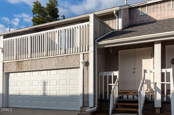 Front view of a house with a garage and stairs leading to the entrance.