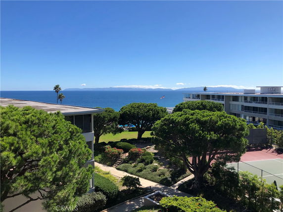 Wide angle view showing trees, buildings, and ocean in the background.