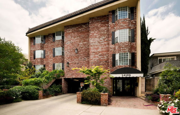 Front view of a multi-story brick building with large windows and a driveway entrance.