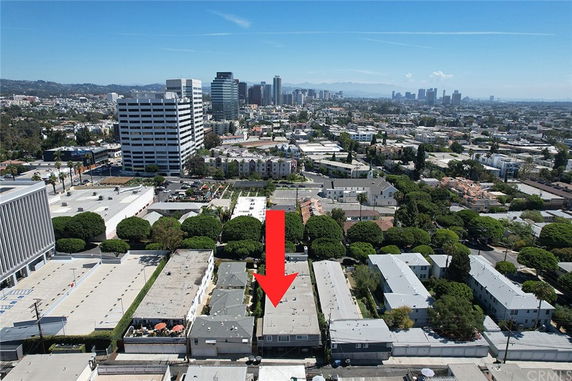 Wide aerial view of urban area with various buildings and cityscape in the distance.