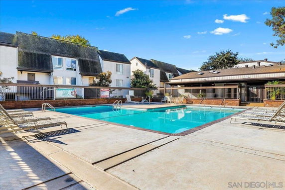 Outdoor swimming pool area with lounge chairs and surrounding buildings.