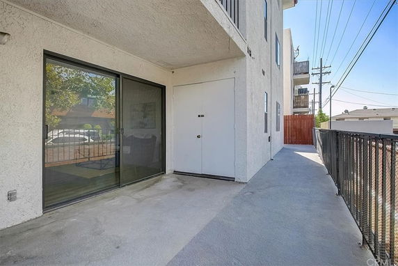 Exterior area of an apartment building with a sliding glass door and railing.