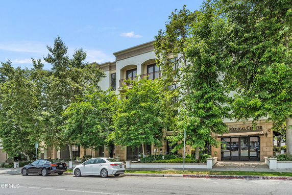 Front view of a medical center building with multiple stories partially obscured by trees.
