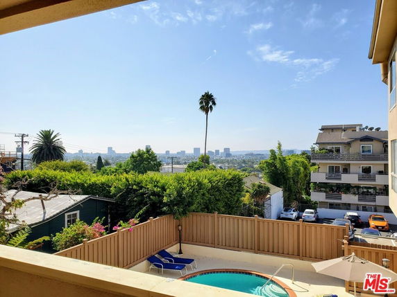 View of cityscape from a building with swimming pool and surrounding greenery.
