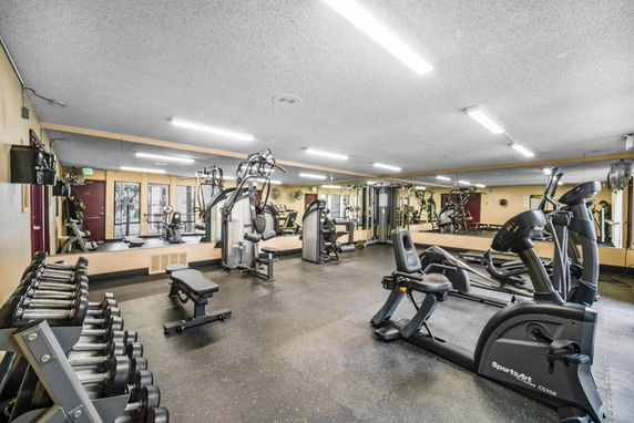 Interior view of a gym with exercise machines and free weights.