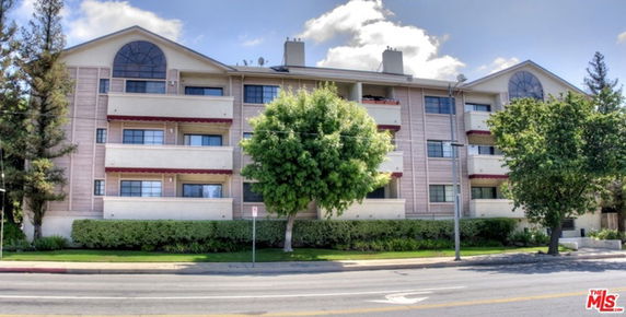 Front view of a multi-story residential building with balconies and large windows.