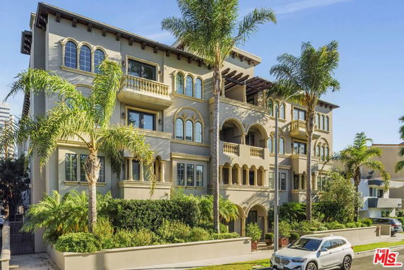 Front view of a multi-story building with arched windows and balconies.