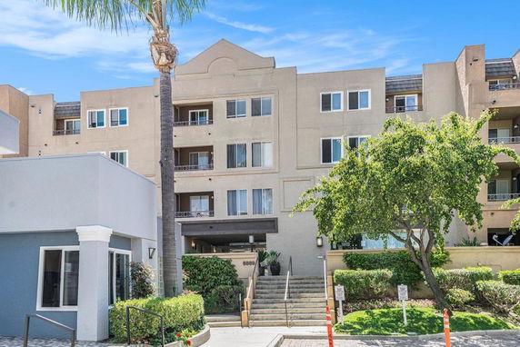 Front view of a multi-story residential building with balconies and a main entrance.