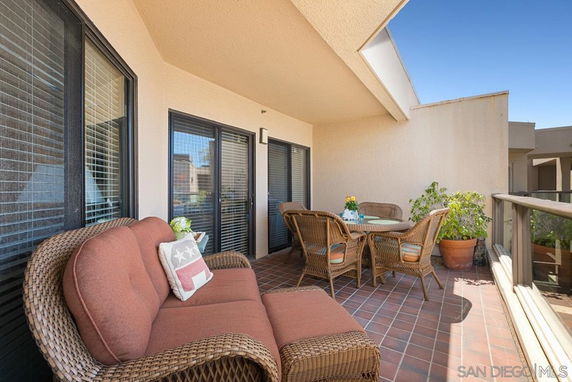 Outdoor patio area with wicker furniture and glass railing.